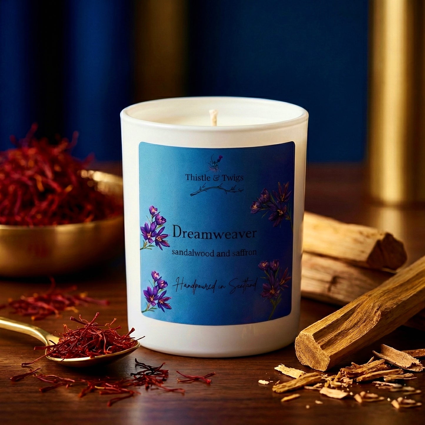 Dreamweaver Soy Wax Natural Candle by Thistle & Twigs - sandalwood and saffron scented candle surrounded by saffron threads and sandalwood sticks on a dark blue background