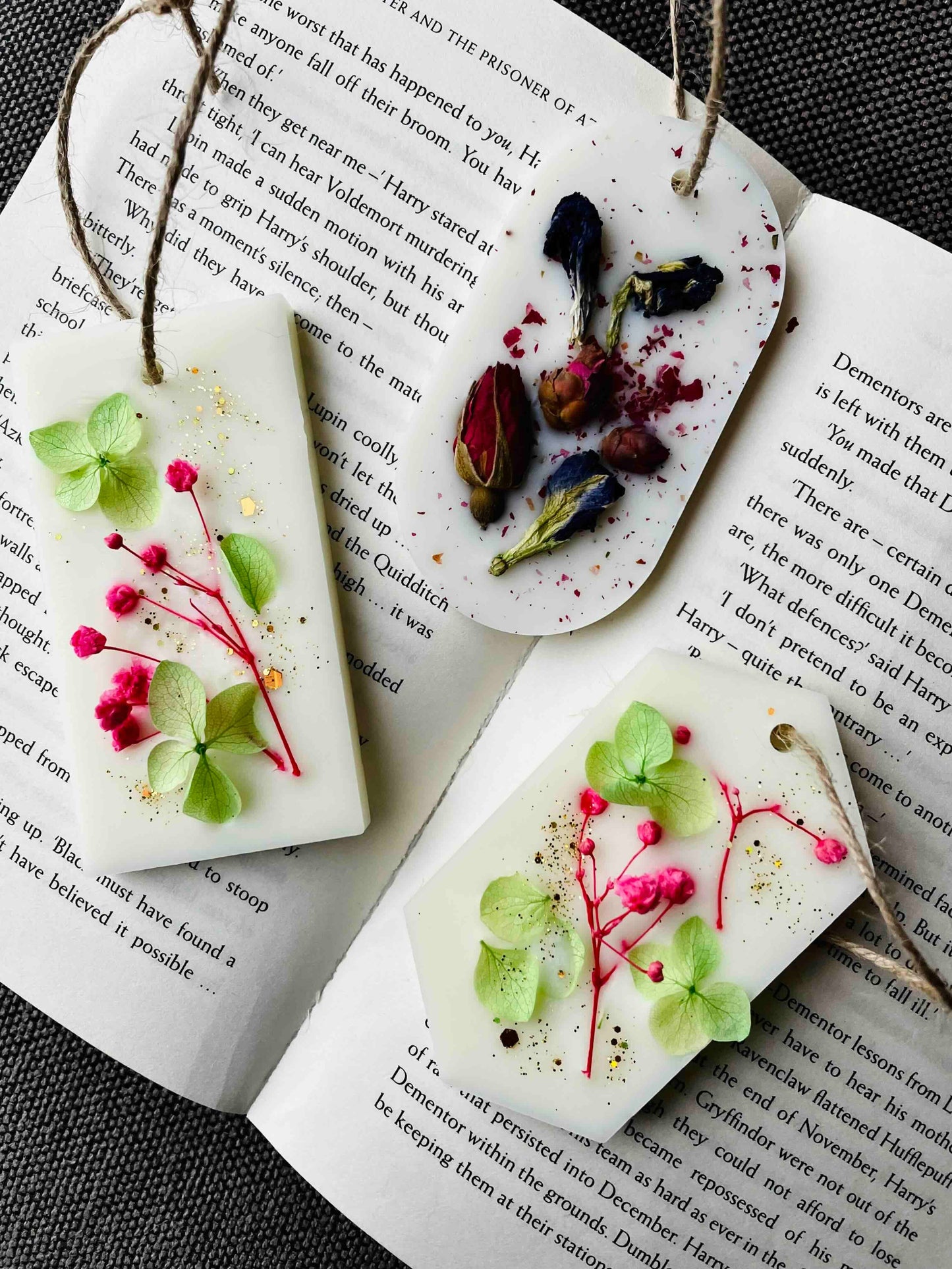 Thistle & Twigs natural wax wardrobe fresheners with jute twine hangers, decorated with pressed dried roses, hydrangeas and pink botanicals, displayed on open book pages