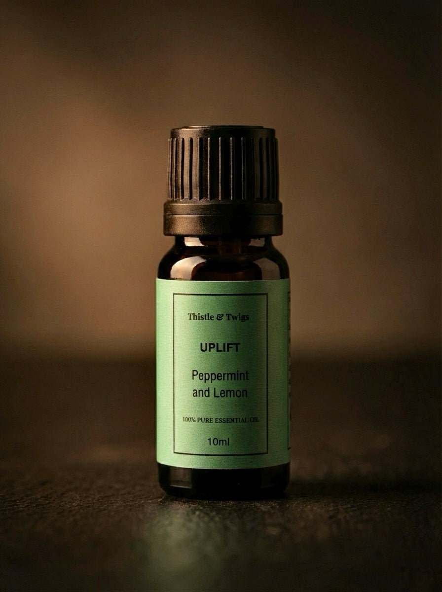Essential oil bottle labeled 'Uplift' with a green label on a dark background