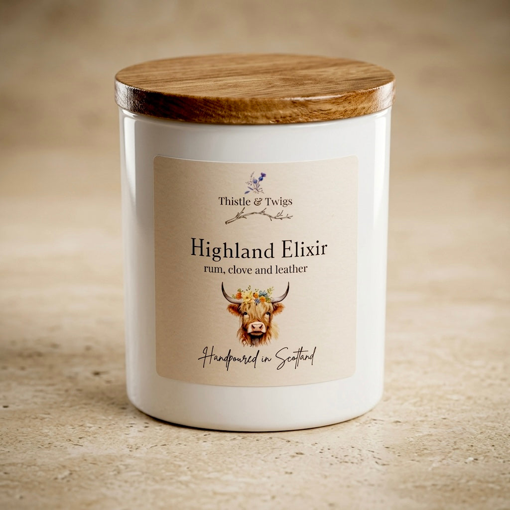 Thistle & Twigs Highland Elixir rum, clove and leather soy wax candle with wooden lid and Highland cow illustration label, hand poured in Scotland