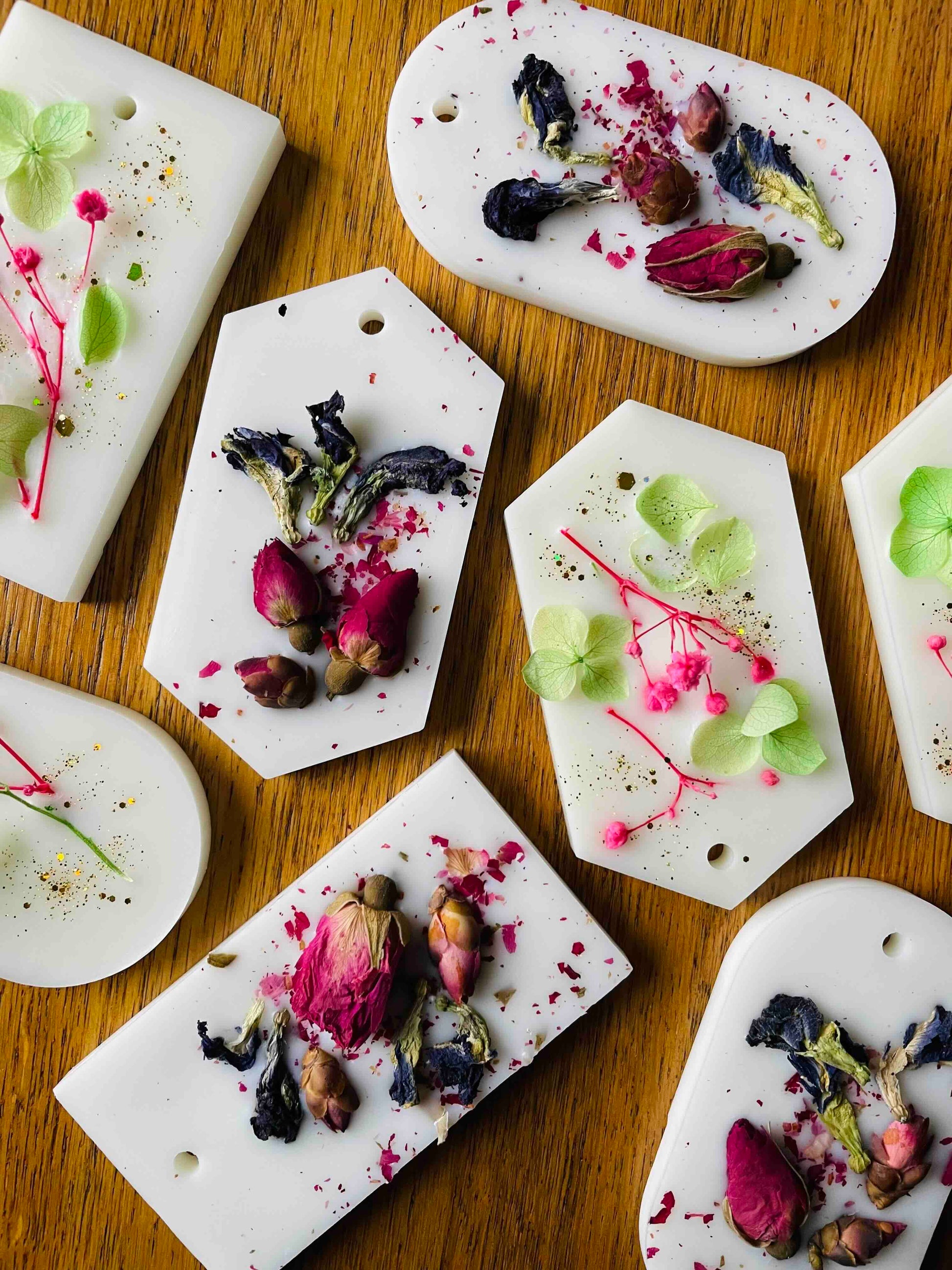 Thistle & Twigs Luxury Wardrobe Fresheners - handmade natural wax sachets in various shapes embedded with dried rose buds, hydrangeas and pressed botanicals, arranged on a wooden surface