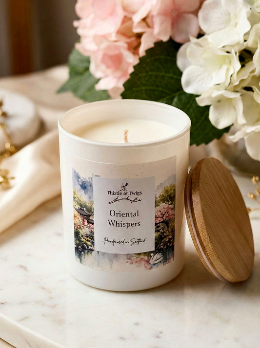 Thistle & Twigs Oriental Whispers hand poured soy wax candle with bamboo lid and watercolour oriental garden label, surrounded by pink and white hydrangeas on a marble surface