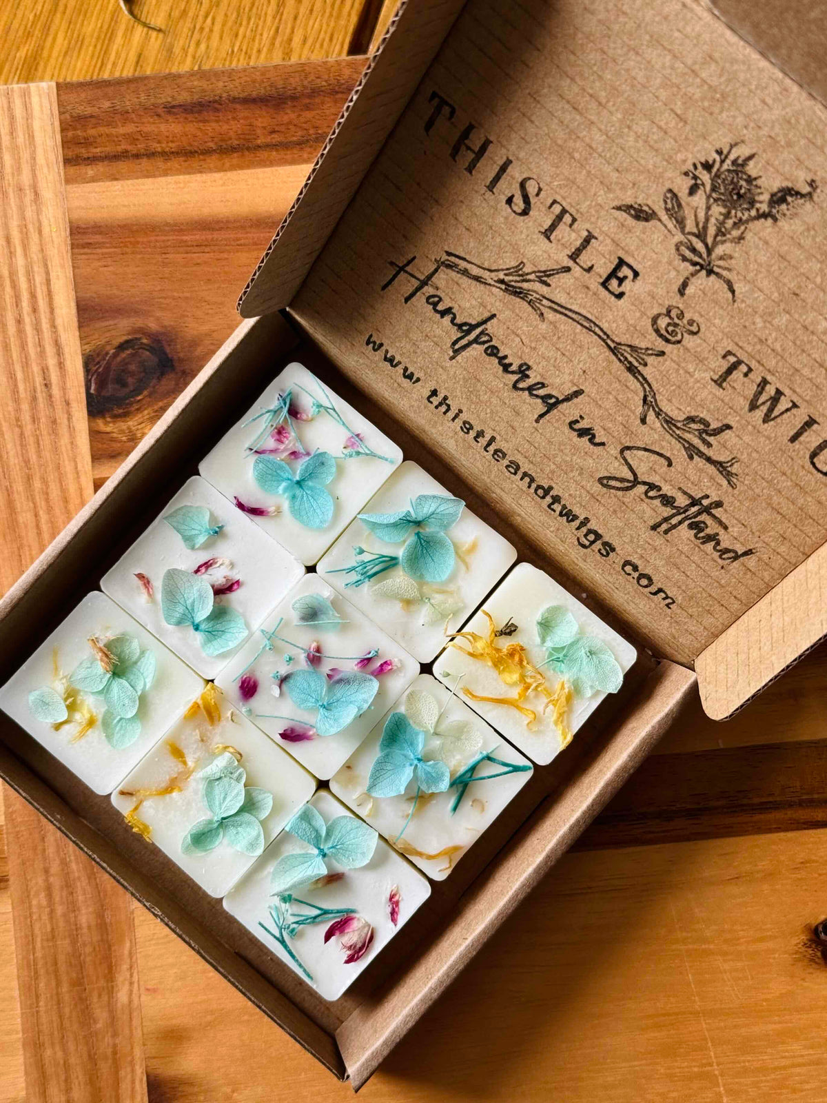 Thistle & Twigs Tonka Botanical Soy Wax Melts - 9 white wax melts embedded with pressed blue hydrangeas, pink rosebuds and yellow botanicals in an open kraft gift box, hand poured in Scotland
