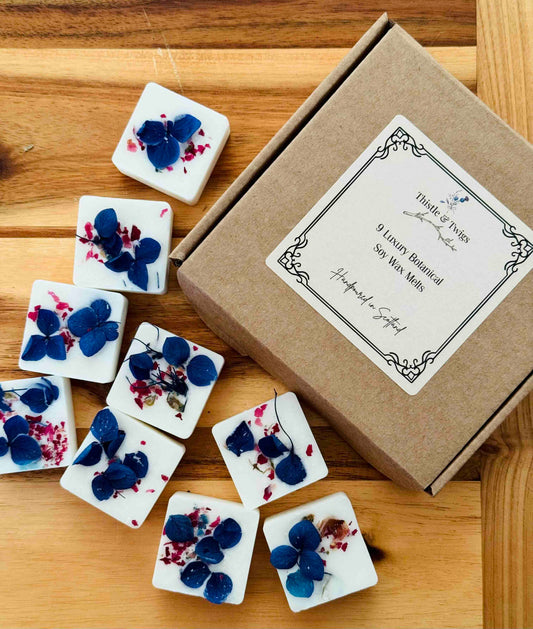 wood-spices-leather-botanical-soy-wax-melt. Decorative soy wax melts with floral designs on a wooden surface next to a cardboard box.
